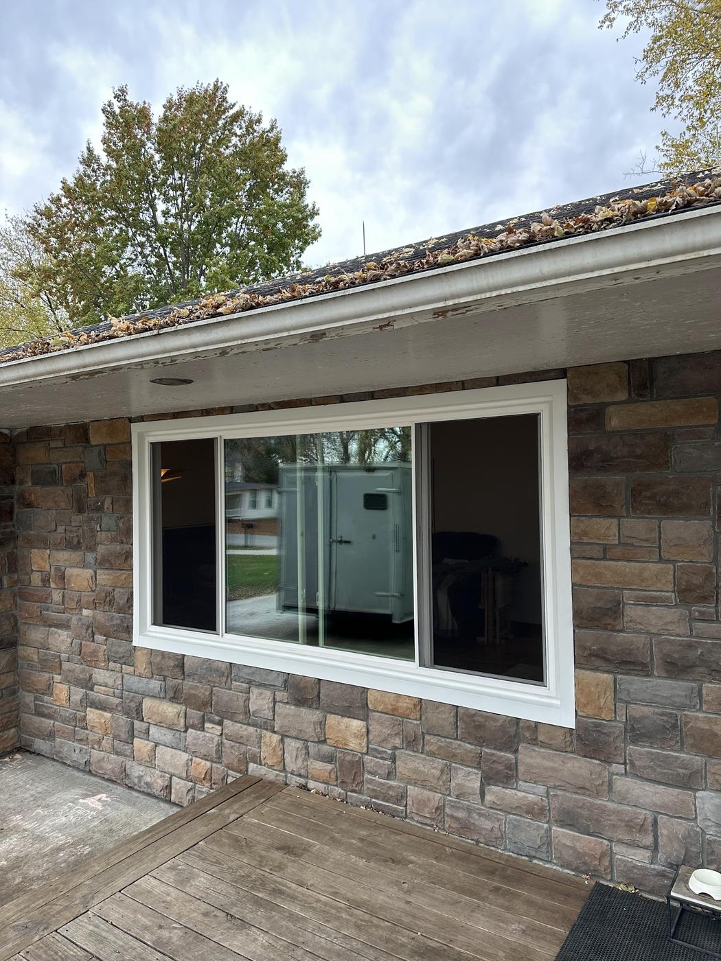 A large completed sliding-window install on a stone-clad house, white frame